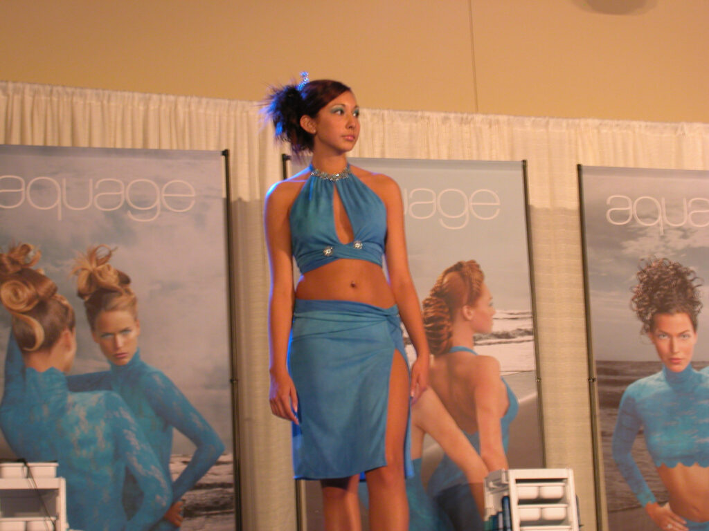 Model in blue dress in front of posters of women in blue dresses.
