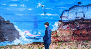 Lone man standing in front of a transparent wall with woman, beach chair and ocean showing through