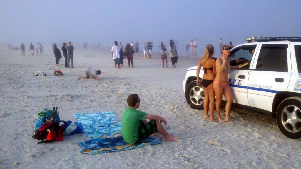 Two girls in bikinis leaning on police car on Jacksonville Beach