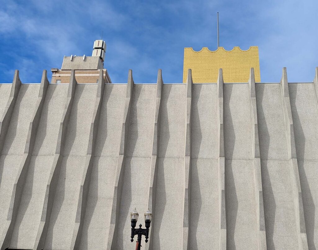 Concrete building facade with jutting pillars above